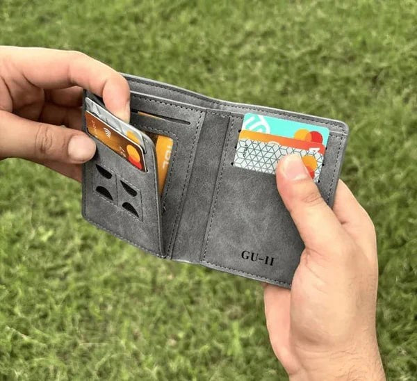 Pak wallets grey leather bi-fold wallet with multiple card slots held in hands outdoors