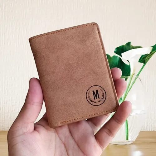 Pak wallets premium tan leather M-wallet with a circular monogram logo held in a hand